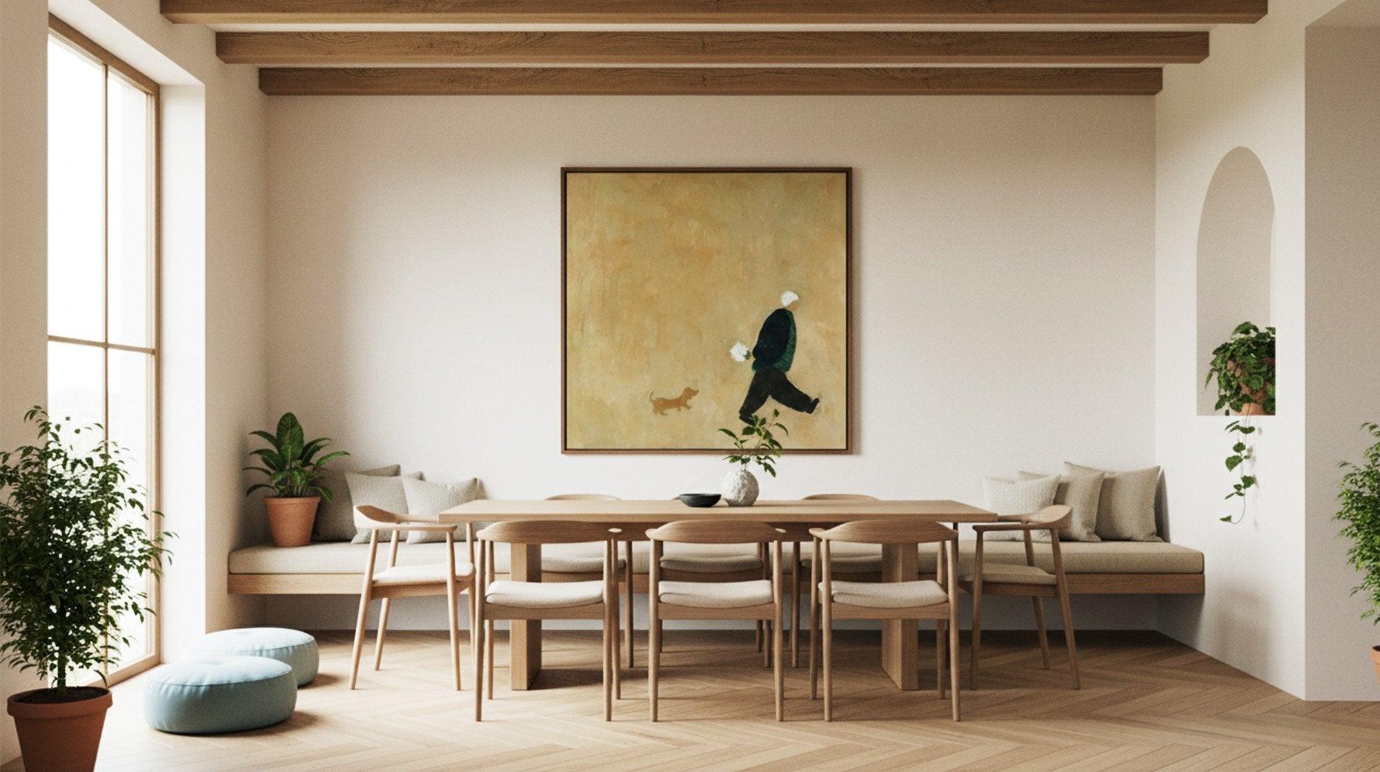 Beige abstract wall art with a dark figure above a light wood dining table in a sunlit neutral dining room.