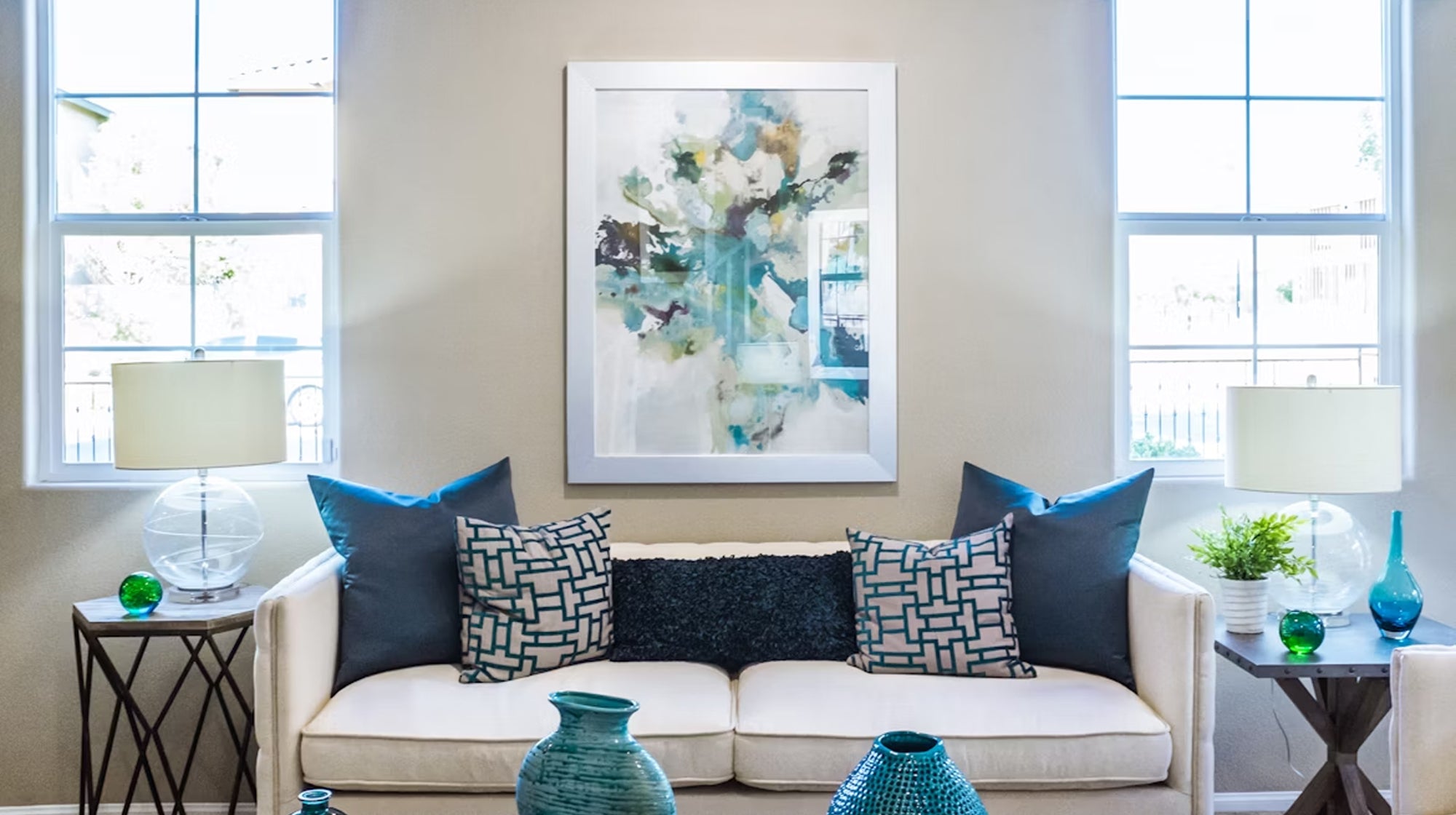 Modern living room featuring abstract acrylic painting above white sofa creating stunning accent wall with blue color palette