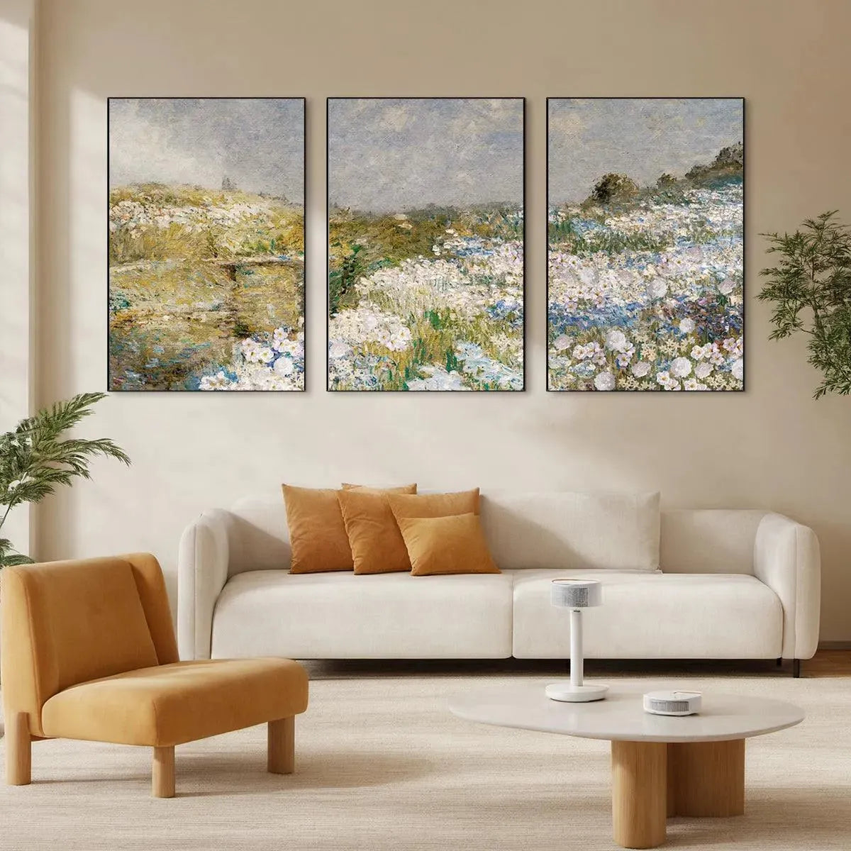 Triptych impressionist wildflower field paintings above cream sofa, muted palette.