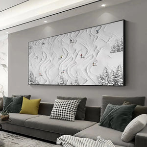 Textured white painting 'Snowy Carve' with skiers on abstract snowy slopes and pine trees, displayed in a living room.