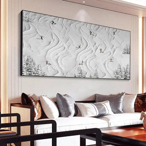 Textured white painting 'Snowy Carve' of skiers descending abstract snowy slopes with pine trees in a living room.