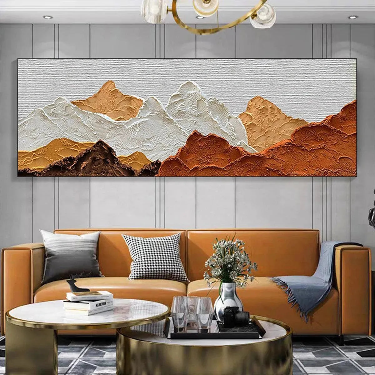 Textured mountain painting in brown, white, and ochre above a modern living room sofa, illustrating scale.