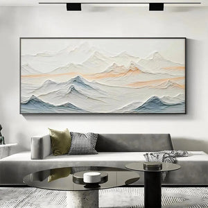 Textured abstract mountain painting in beige, blue, and peach hues, displayed above a modern sofa in a living room setting.