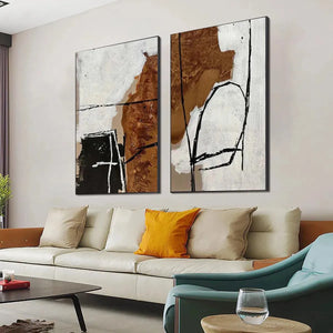 Brown & white abstract diptych vertical wall art set, featuring textured paint and bold black lines, shown in a room.