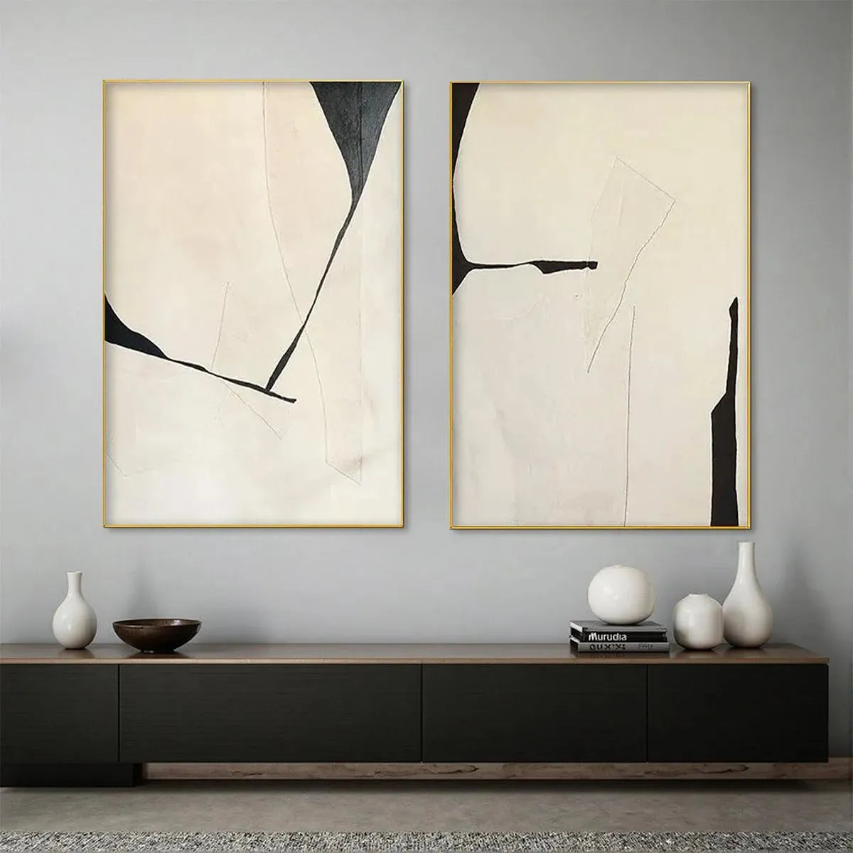 Minimalist diptych: vertical beige & black abstract art with gold frames above credenza.