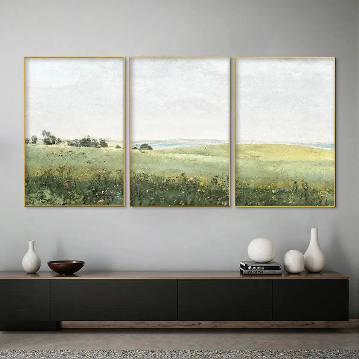 Set of 3 minimalist green field landscape paintings with gold frames, displayed in a modern room setting.