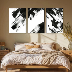 Black and white abstract triptych wall art set above a wooden bed in a bedroom