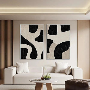 Two vertical abstract paintings, black & beige organic shapes, minimalist style, shown in a modern living room.