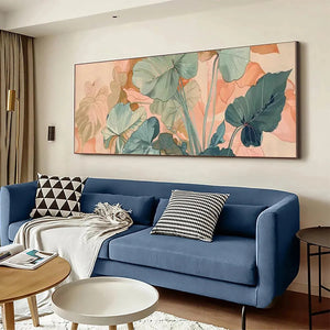 Panoramic botanical art with teal & sage green tropical leaves on peach background, over a blue sofa.