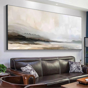 Misty Mountain Lake Panoramic artwork in muted earth tones above a brown leather sofa, showcasing serene landscape wall art.