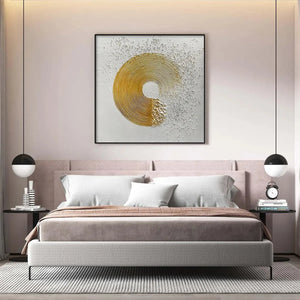 Golden Harmony abstract painting in a bedroom, featuring textured gold concentric circles on a white background.