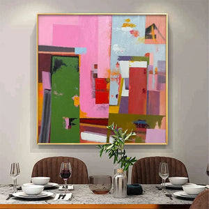 Abstract Urban Scene by Willow Davies, square wall art with pink, green, and red blocks in a gold frame.