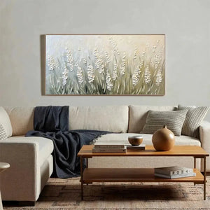 Elodie Dubois Textured Meadow floral landscape painting in green and white, displayed above a light sofa in a living room.