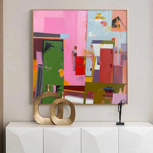 Abstract Urban Scene painting by Willow Davies, square wall art. Pink, green, and red blocks, gold frame, modern decor.