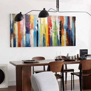 Colorful abstract vertical stripes painting in modern dining room with wooden table and black pendant lights.