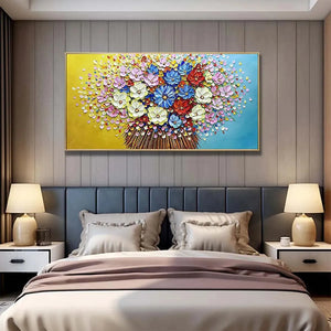 Textured impasto floral wall art with vibrant multicolor flowers on yellow and blue gradient background, displayed above modern gray bedroom headboard.