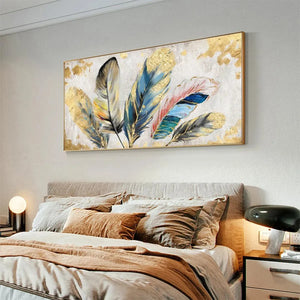 Gold leaf feather painting, horizontal wall art. Blue, teal, pink, gray, gold feathers with gold accents, shown above a bed.