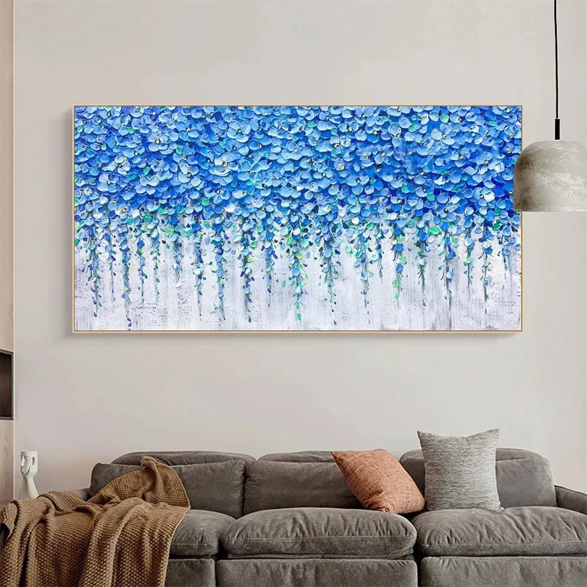Blue Wisteria textured impasto painting in gold frame above a gray couch, showcasing the beauty of blue floral blossoms.