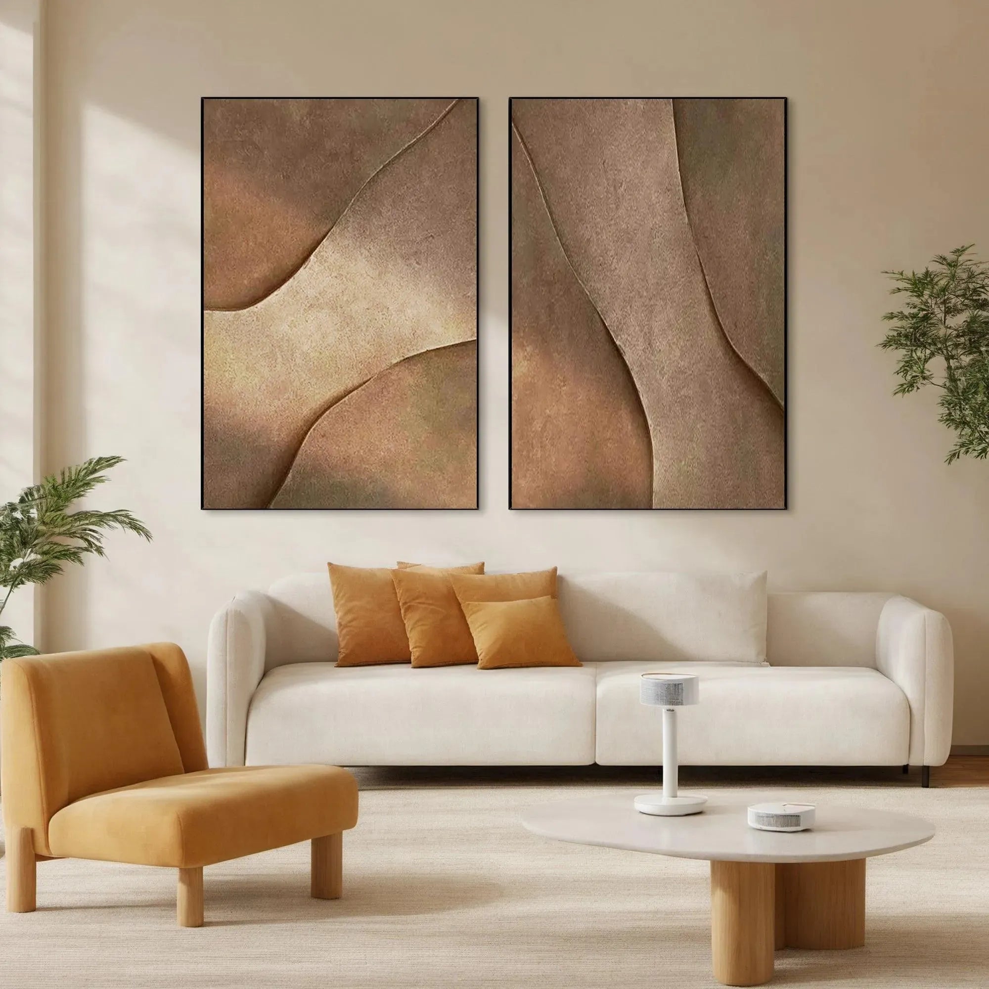 Set of 2 framed brown abstract paintings with textured curves above cream sofa, styled in a modern living room.
