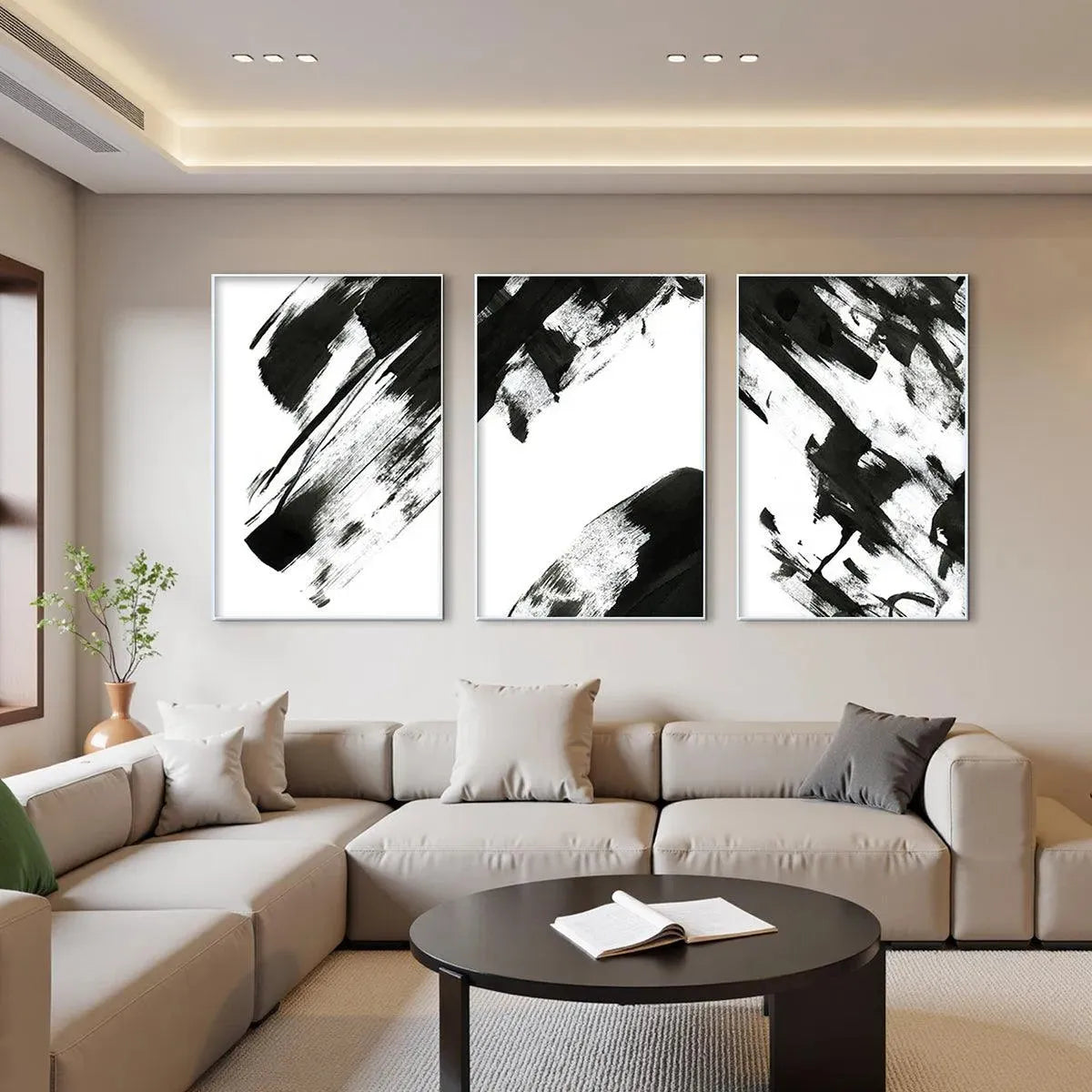 Black and white abstract triptych wall art displayed above a sectional sofa in a living room.
