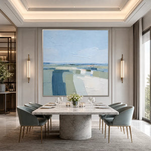 Textured abstract coastal landscape painting in blue, green and white above modern dining table