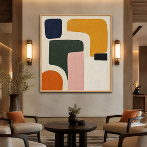 Modern organic shape abstract wall art with bold blue, mustard, green, pink and orange forms in a wood frame displayed in a luxury hotel lobby.