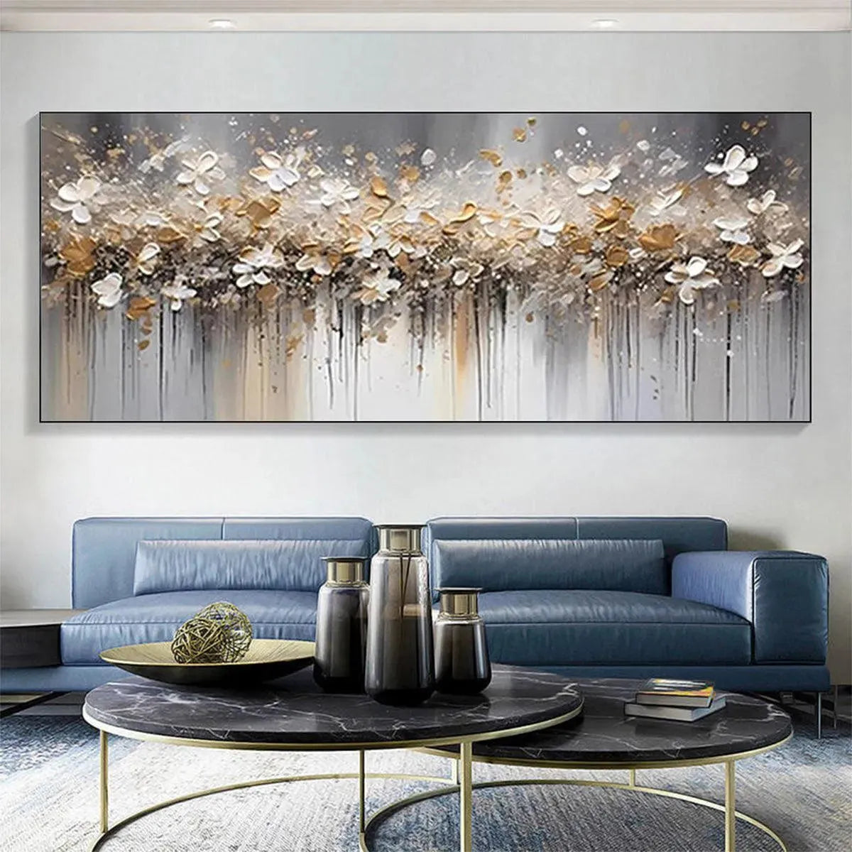 Panoramic abstract floral painting, white and gold blossoms, dripping paint, displayed above blue sofa in modern living room.
