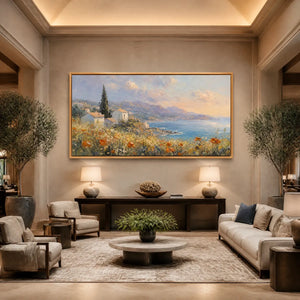 Framed coastal oil painting with poppies and houses, mounted on the wall of a transitional living room.