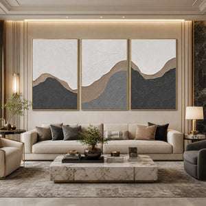 Textured earth-tone abstract triptych wall art in gold frames above a modern sofa