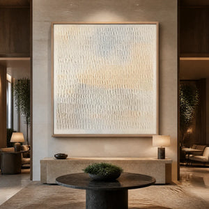 White textured minimalist abstract wall art in a gold frame displayed in a luxury hotel lobby.