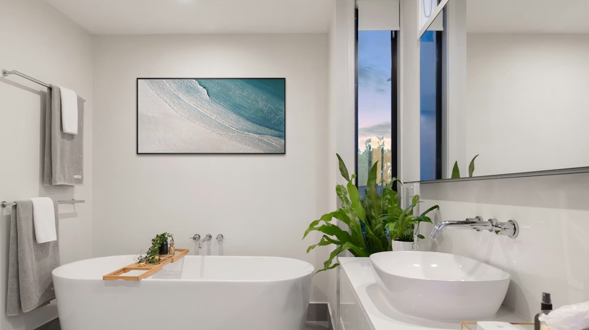 A modern bathroom with a freestanding tub, a wooden bath tray, and a serene abstract painting of a beach and ocean waves on the wall.