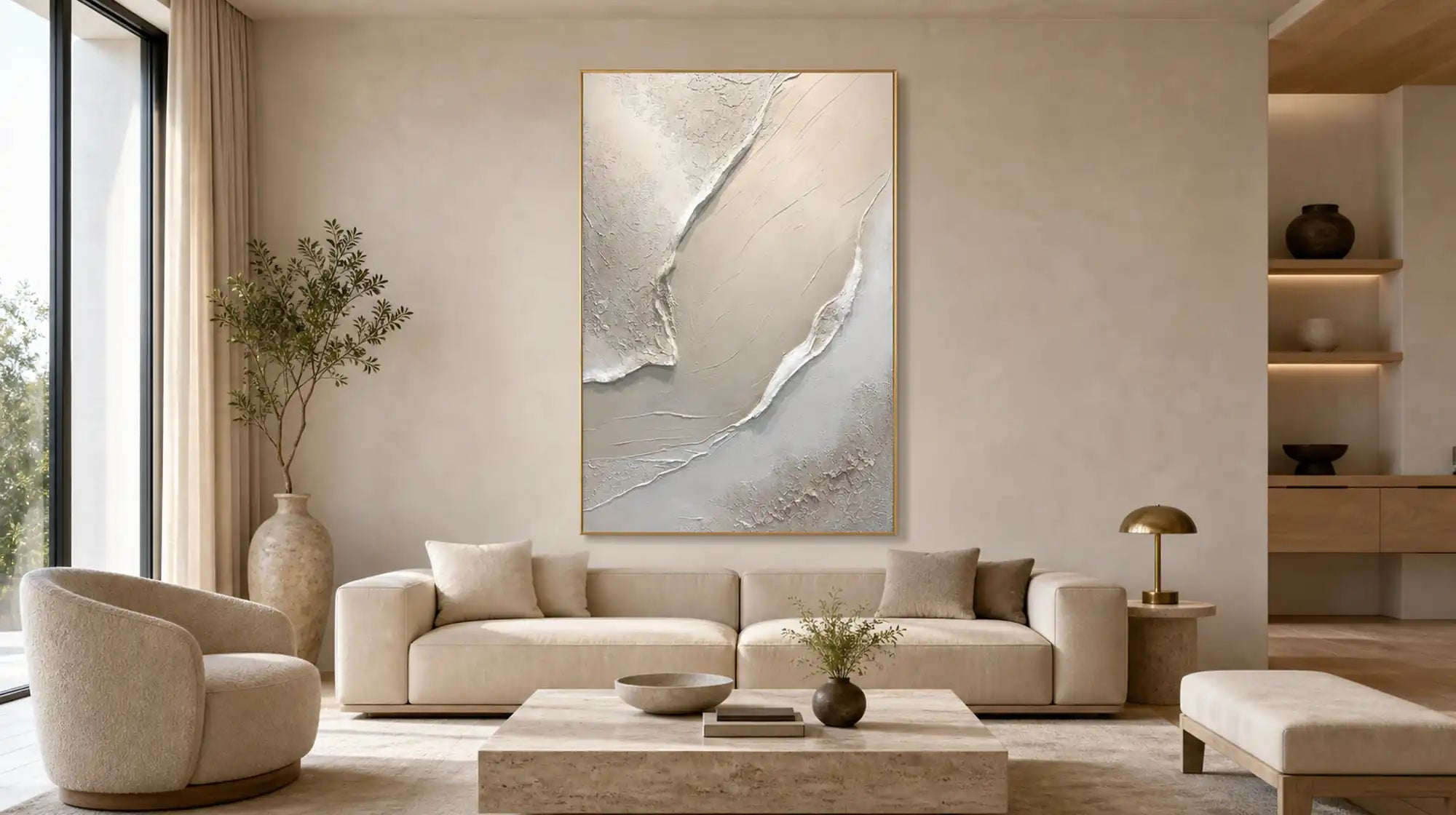 Neutral white textured abstract wall art framed in gold, displayed above a cream sofa in a bright modern living room.