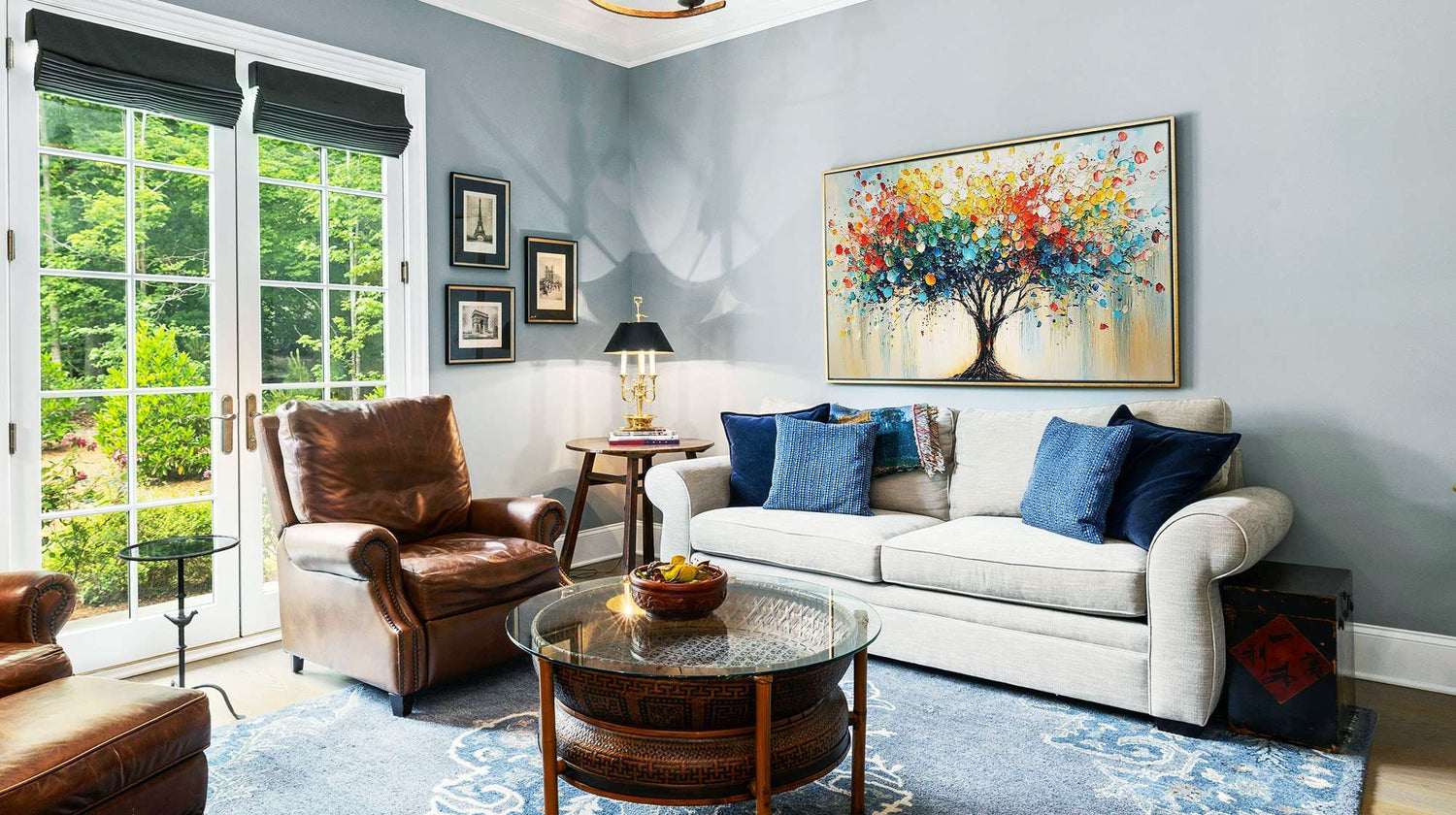 Colorful tree painting above a white sofa in a bright living room with blue accents.