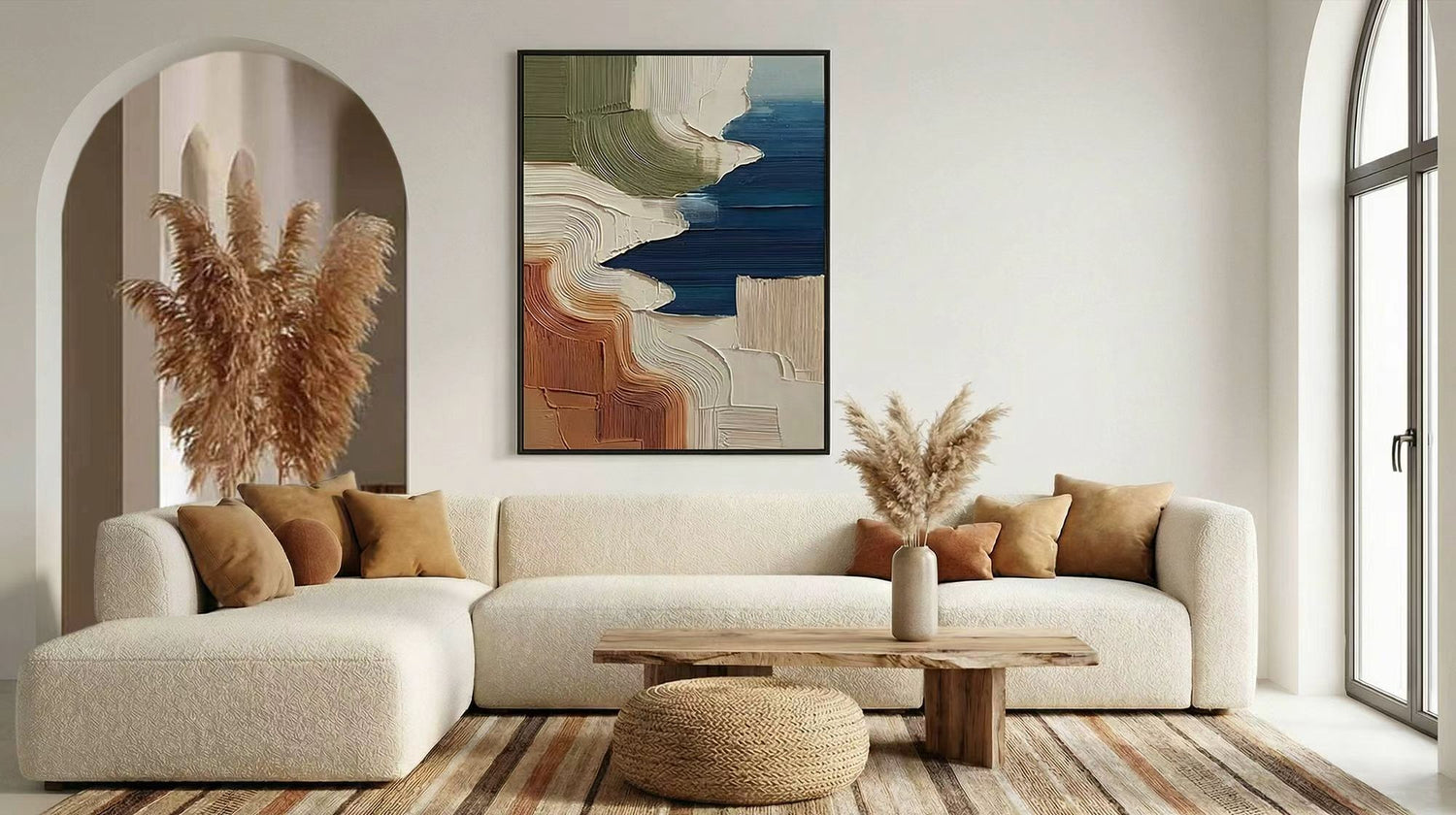 Neutral living room with curved sofa, pampas grass, and a raised texture painting in blue, olive, cream, and terracotta.