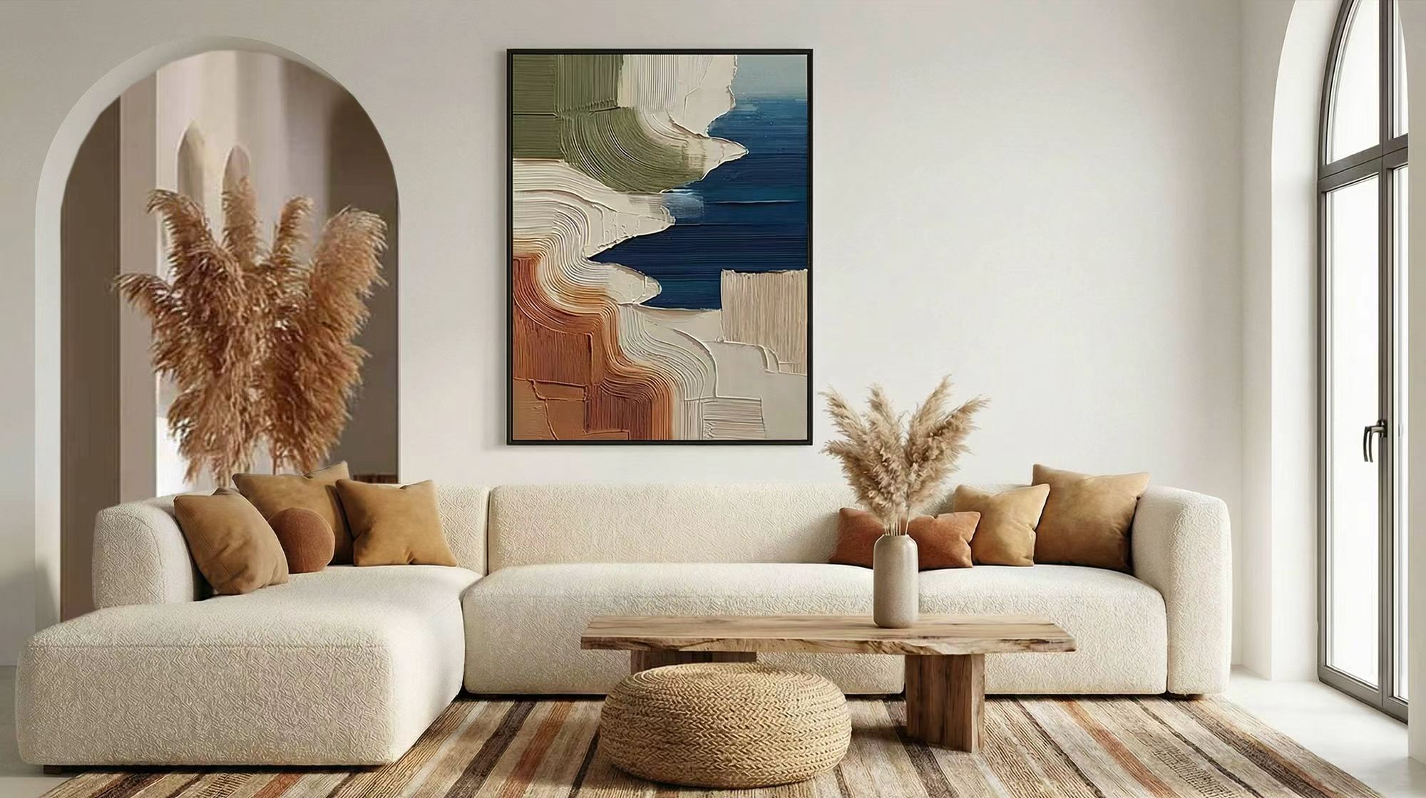 Neutral living room with curved sofa, pampas grass, and a raised texture painting in blue, olive, cream, and terracotta.