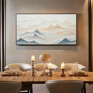 Textured abstract mountain landscape painting in beige and blue, framed and hung above a dining table.