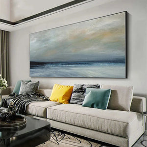 Liam O'Connell's Twilight Coast panoramic painting in muted blues and grays above a sectional sofa in a living room.