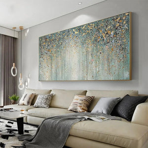 Textured abstract painting 'Golden Rain' with teal-green, gold, and gray flecks. Lifestyle setting.