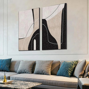 Two vertical abstract paintings: beige, black, white organic shapes and clean lines on textured canvas, above sofa.