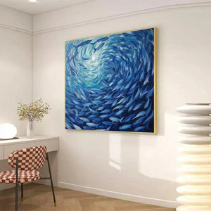 Oceanic Whirl original painting featuring swirling school of fish in blue tones, displayed in modern workspace.