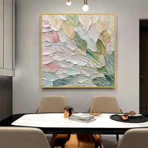 Square impasto painting 'Pastel Dream' with thick textured pastel leaf shapes in a gold frame, displayed in a dining room.