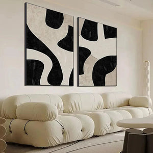 Black and beige abstract diptych wall art by Javier Ramirez shown in a modern living room with a plush sofa.
