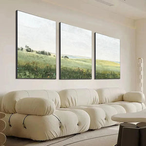 Set of 3 Liam O'Connell minimalist green field paintings with black frames above a cream sectional sofa.