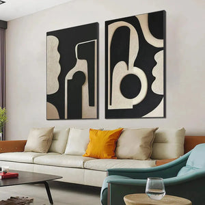 INK BLOT DUO: 2 framed black and beige abstract paintings with textured organic shapes above a cream sofa.