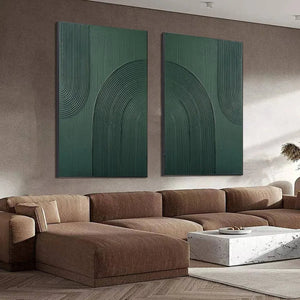 Two vertical green textured abstract paintings with raised arches above a sectional sofa in a living room.