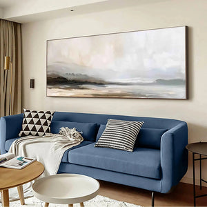 Liam O'Connell's Misty Mountain Lake Panoramic wall art in muted earth tones above a blue sofa.