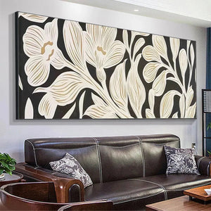 Panoramic wall art with cream and gold floral design on black background, displayed above a dark leather sofa.