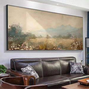 Panoramic meadow landscape painting with wildflowers and mountains, showcased above a dark leather sofa.