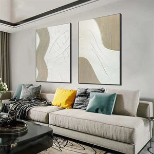 Two minimalist textured paintings with raised white abstract lines on beige background, in a living room setting.