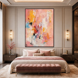 Vertical textured abstract oil painting in pink, blush, yellow and orange above a bed